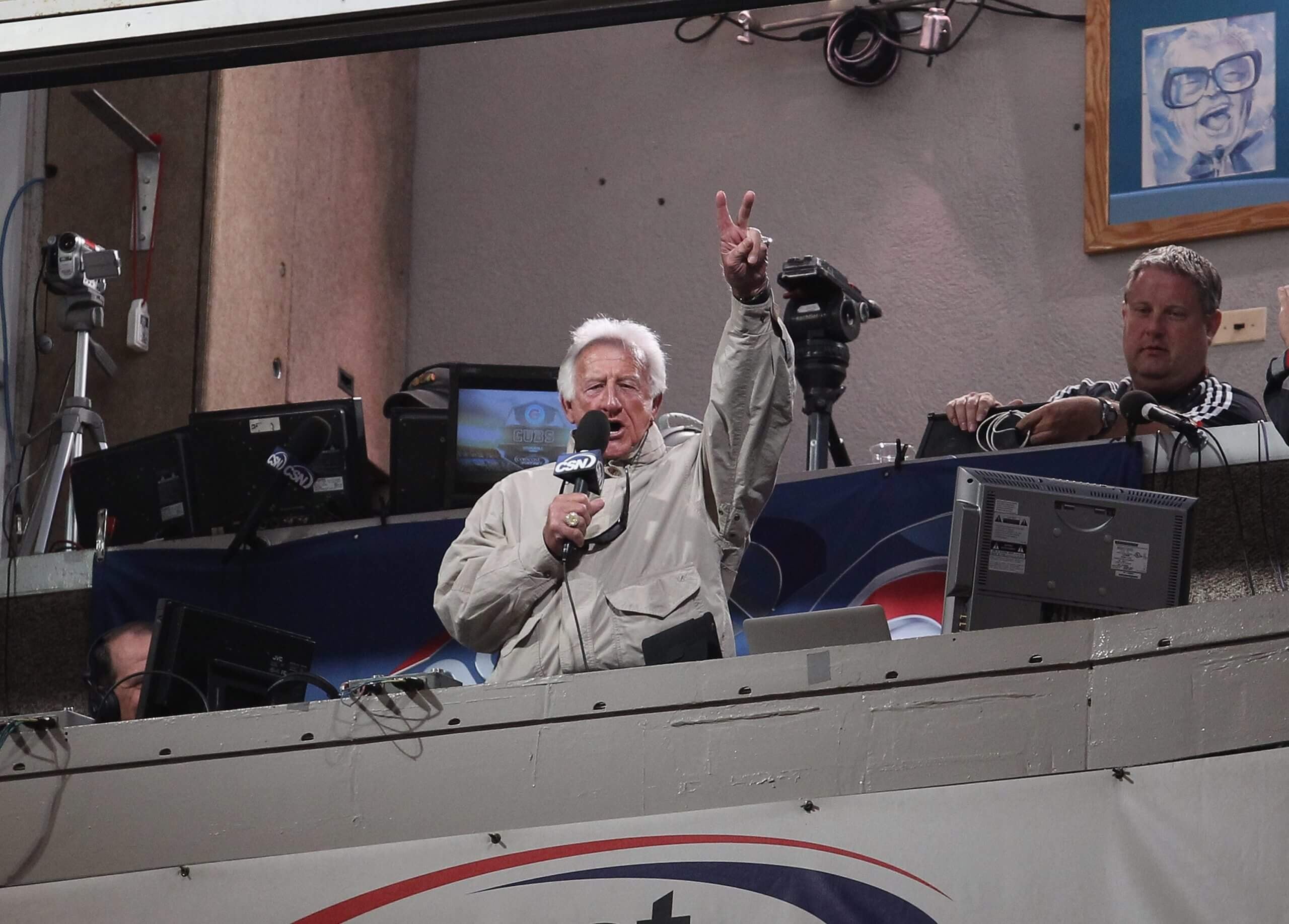 Bob Uecker leans out of the booth to sing "Take Me Out to the Ballgame" at Wrigley Field in 2011. (Jonathan Daniel / Getty Images)