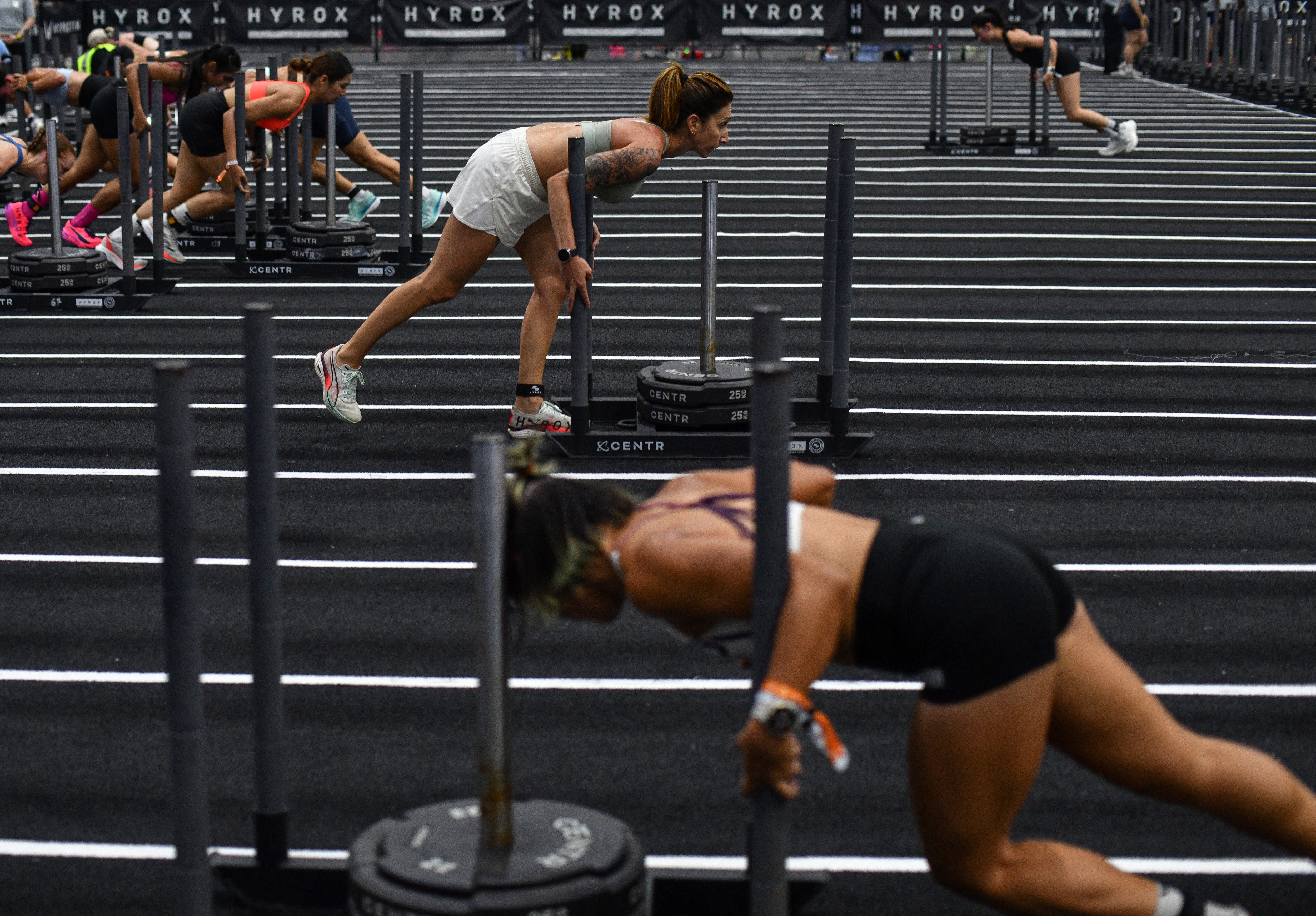 Hyrox, a timed fitness competition, takes place in 36 countries, offering participants a global community. Community is a big part of why people pay for experience workouts, personal trainer Nicole Greco-Peepas says
