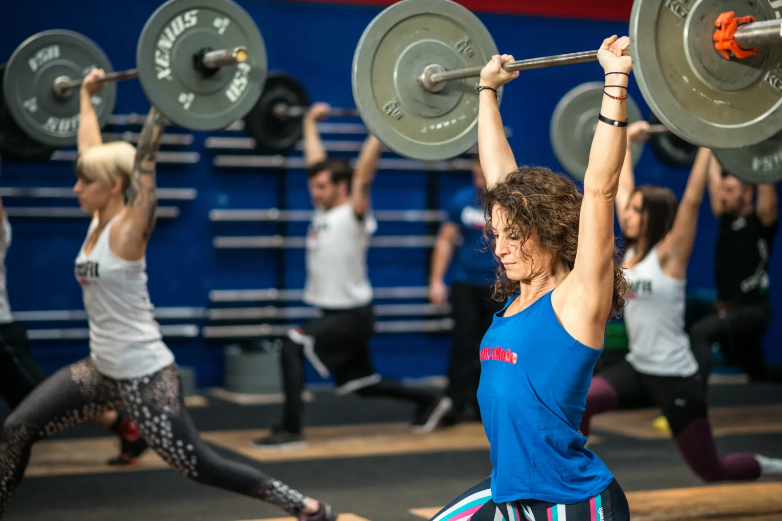 Stock image: A fitness community of students learning weightlifting techniques during a gym class.