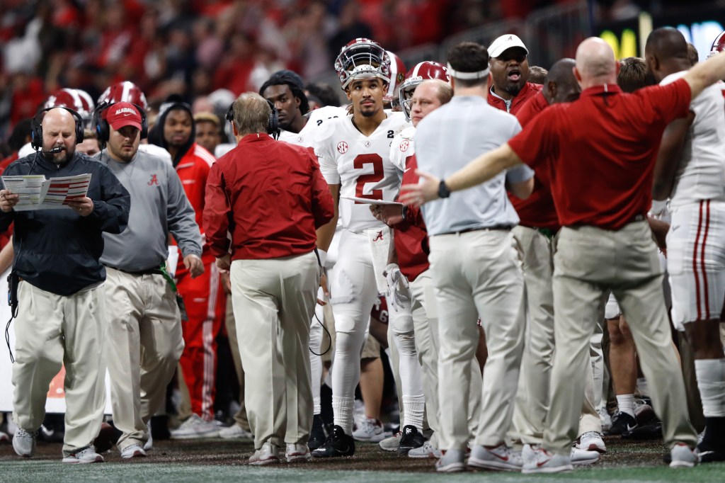 Alabama Crimson Tide quarterback Jalen Hurts (2) stands on the sideline surrounded by coaches and staff members during the CFP National Championship.