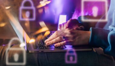 Female hands typing on a laptop in neon light. A lock as a symbol of cybersecurity on a foreground.