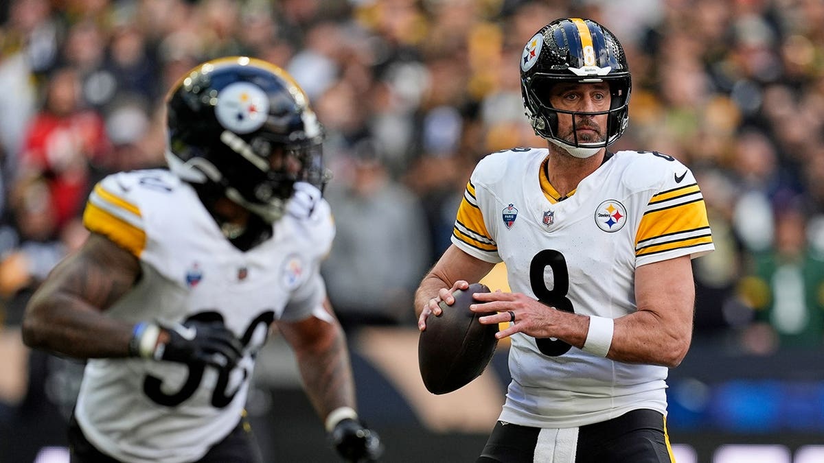 Aaron Rodgers, wearing number 8, looks to pass during an NFL game.