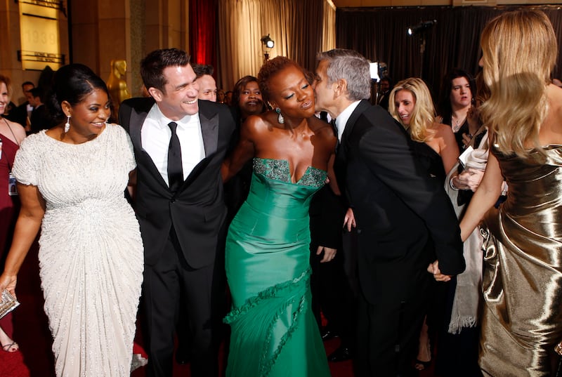 Best supporting actress nominee Octavia Spencer (L) and "The Help" director Tate Taylor (2nd L) watch as best actor nominee George Clooney (2nd from R) gives a kiss to best actress nominee Viola Davis (C) on the red carpet at the 84th Academy Awards in Hollywood, California, February 26, 2012.   REUTERS/Lucas Jackson   (UNITED STATES) (OSCARS-ARRIVALS)