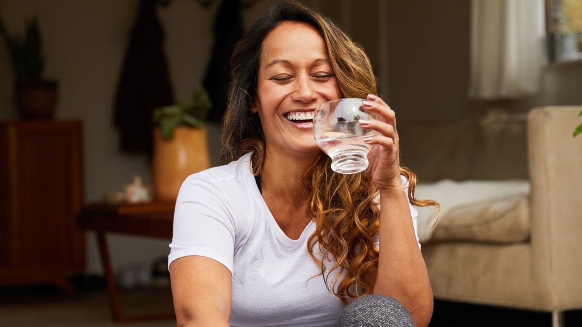 A woman laughing with her eyes closed while sitting on her patio steps.