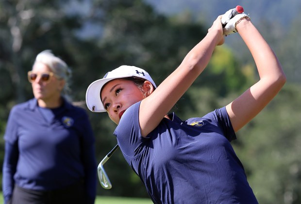 UCSC's Jocelyn Choi hits her tee shot on Pasatiempo's 18th hole on Monday as head coach Paulette Pera watches. (Shmuel Thaler - Santa Cruz Sentinel)