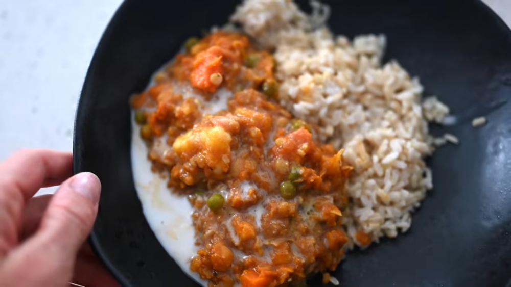 Erin holds a bowl of lentil and vegetable mixture served over brown rice as part of her plant-based high-protein diet