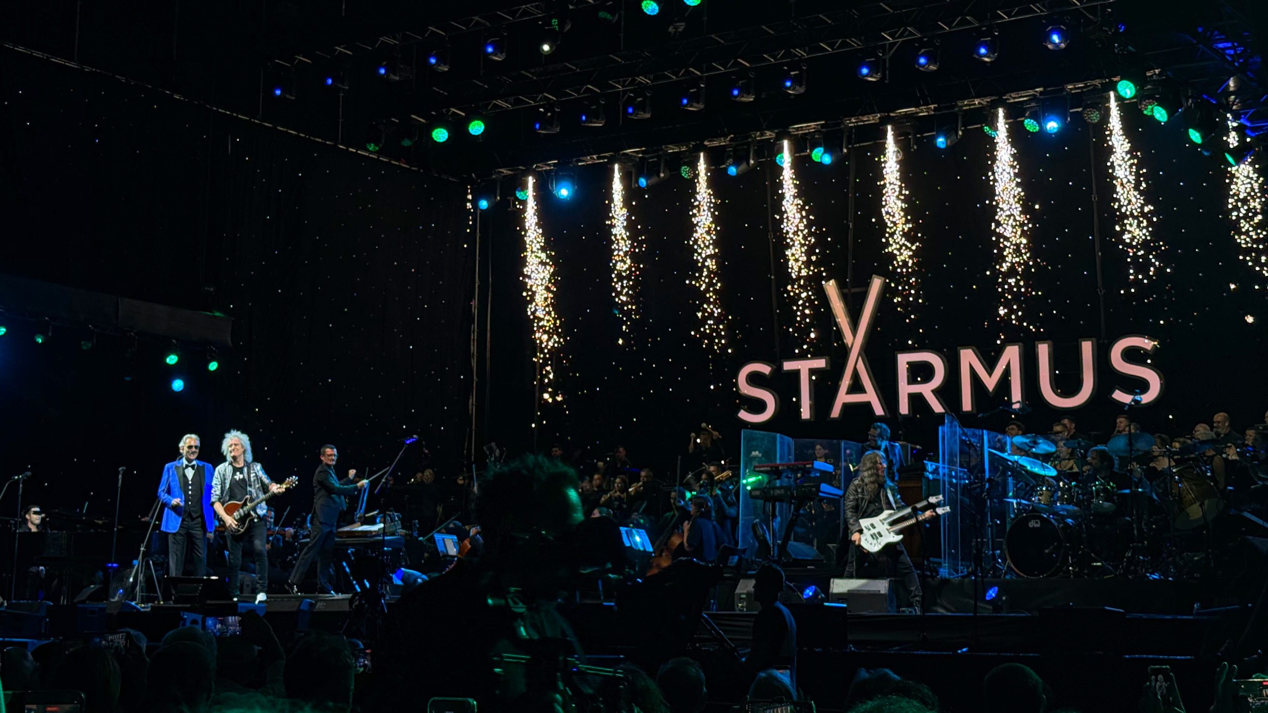stage with musicians and the word starmus written at the back. left is Borcelli, then Brian May and on the right Ron 'bumblefoot' Thal