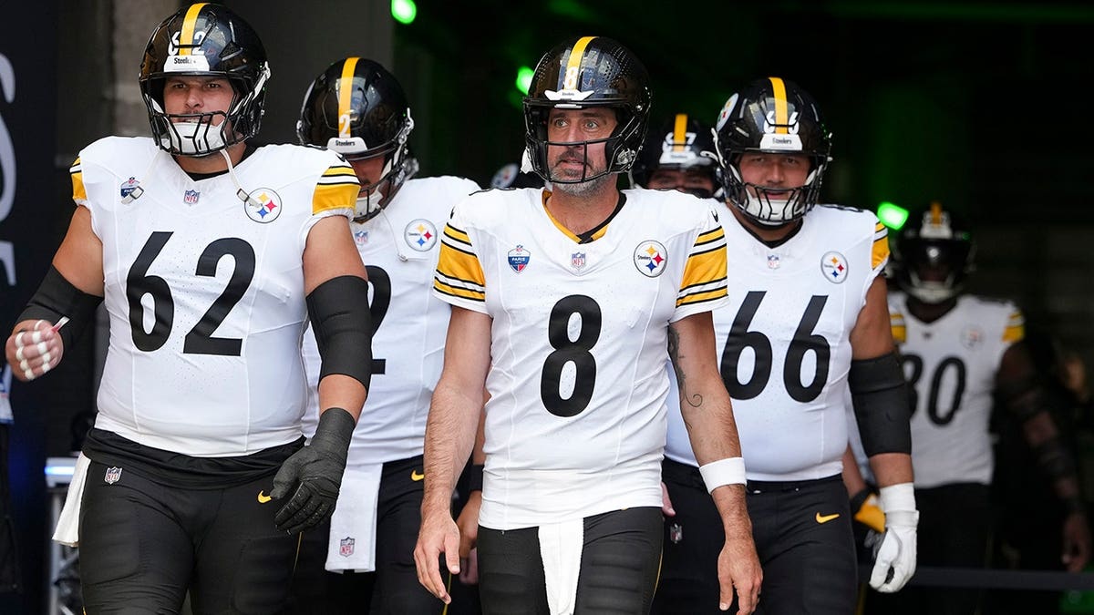 Aaron Rodgers walks on the field with Pittsburgh Steelers teammates before a game.