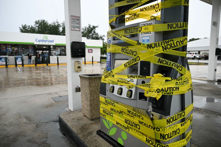 Workers cordon off a petrol pump with yellow tape at a gas station in Navarre, Florida, on October 9, 2026, as Hurricane Isaias moves north toward the Florida Panhandle. [AFP]