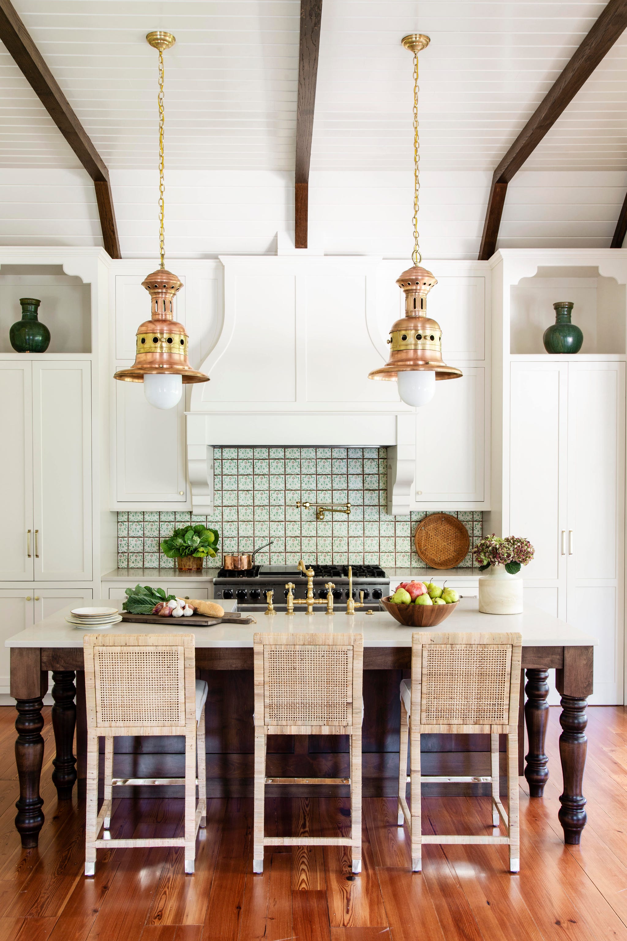 a cottage kitchen with white cabinets and a pair of copper light fixtures
