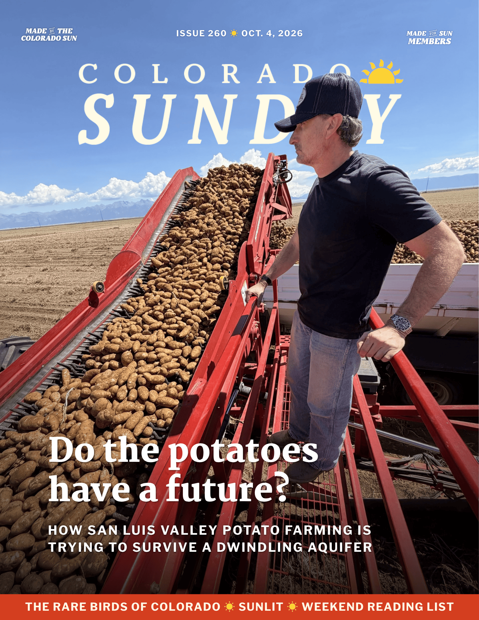 A man stands on farming equipment beside a large pile of potatoes in a harvested field, showcasing the results of potato farming under a clear sky.
