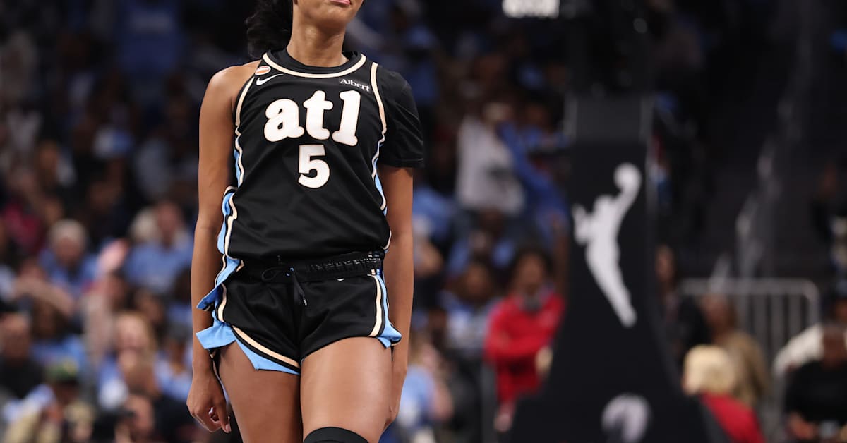 A female basketball player in a white "DREAM" jersey with number 6 gestures during a game, focused and determined.