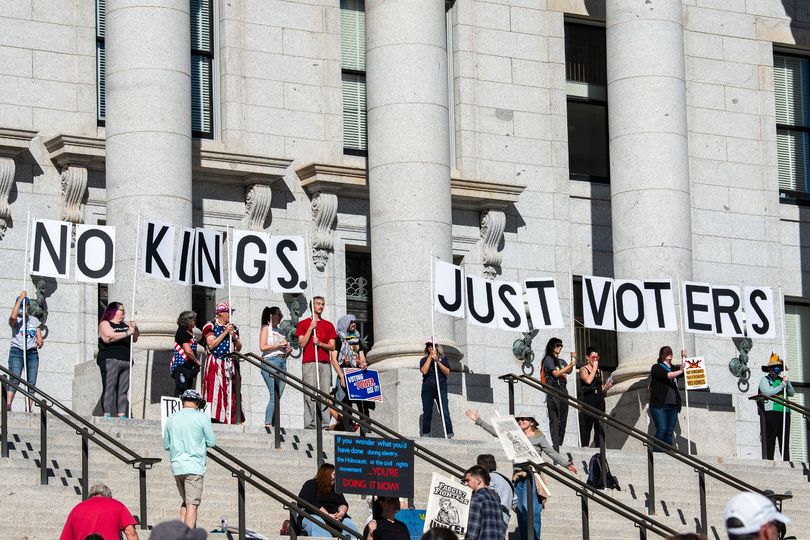 Demonstrators hold large signs during the No Kings: Vote Early rally in Salt Lake City, Utah, on October 17