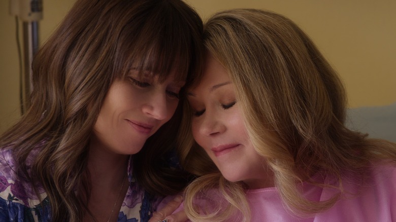 Judy and Jen tilt their heads toward each other, softly smiling, in 