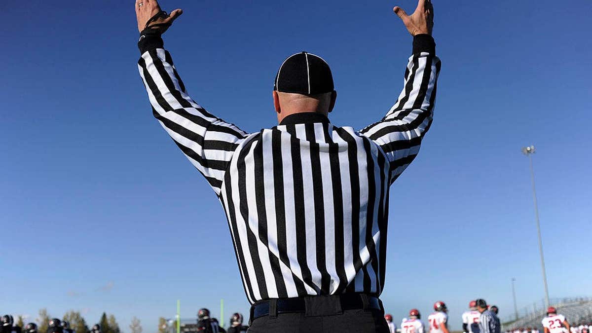 An official signals a successful extra point kick during a Fairview High School football game.