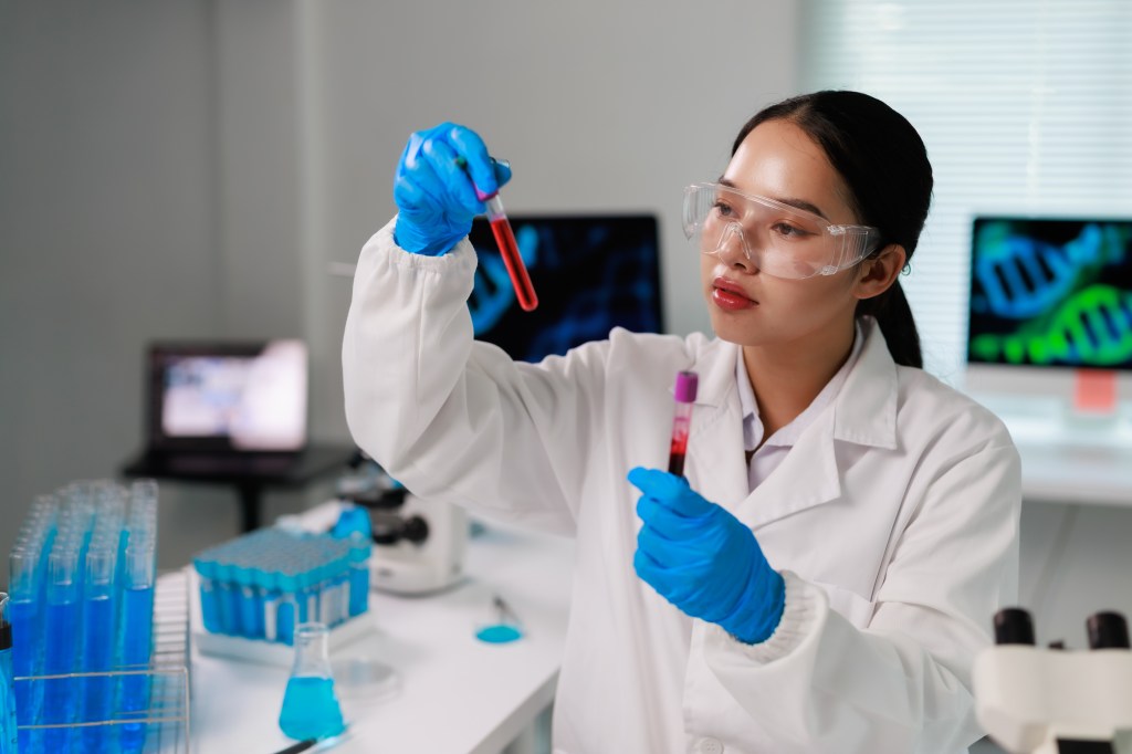 A female scientist holding test tubes with blood samples in a laboratory.