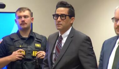 luciano frattolin stands in court between a sheriff's deputy and a lawyer