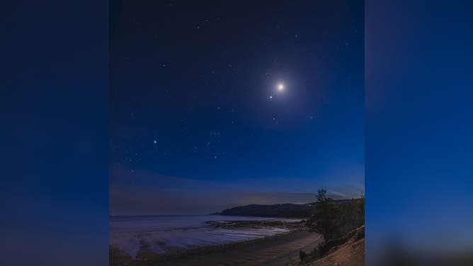 This vertical panorama frames the bright winter stars and constellations setting in the twilight over the Bay of Fundy on an early April evening. At centre is Orion with its distinctive trio of Belt stars, as well as reddish Betelgeuse above and bluish Rigel below. Taurus is to the right of Orion, with the Pleiades cluster, while Canis Major and its bright star Sirius is to the left.
