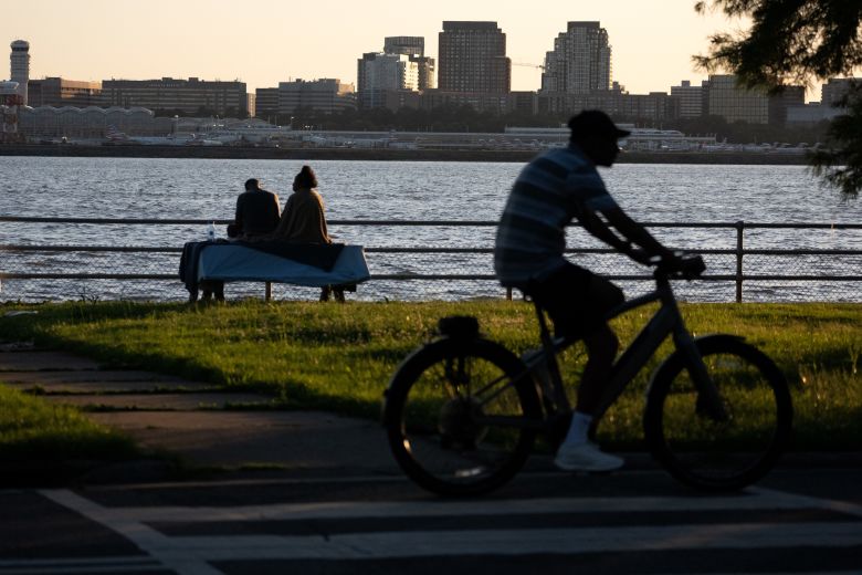 People look out over the Potomac River as cyclists pass on Ohio Drive, the road that rings Hains Point.