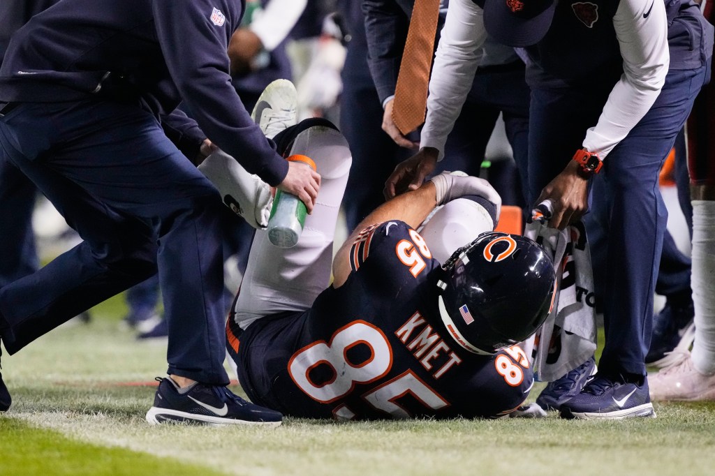 Chicago Bears tight end Cole Kmet (85) holds his right leg after suffering an injury.