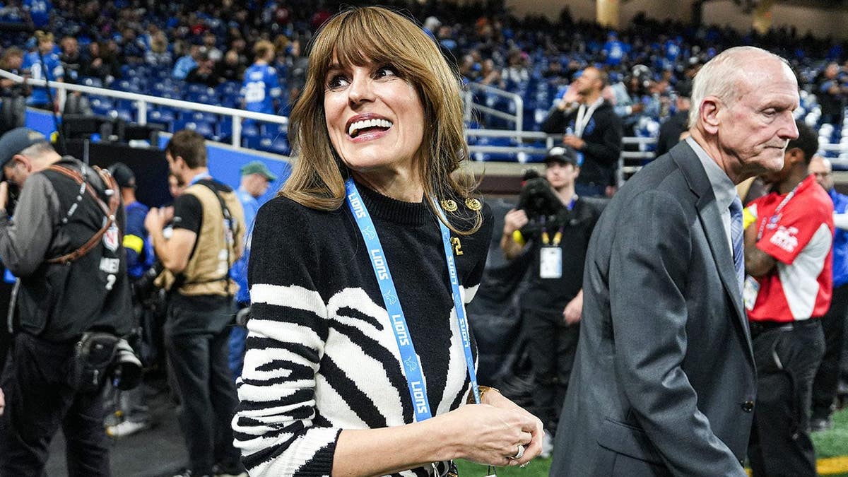 Holly Campbell, wife of Detroit Lions head coach Dan Campbell, waves at fans during warmups.