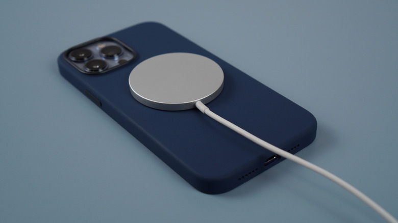 A magnetic charger attached to the MagSafe portion of an iPhone phone case.