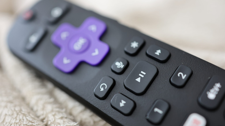 A close-up shot of a Roku remote on top of a blanket.