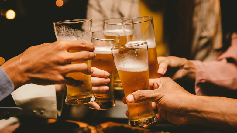Close-up of a group of people toasting with tall beer glasses