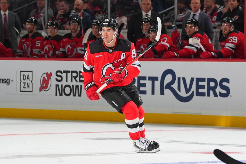 Jack Hughes of the New Jersey Devils skates with the puck on the ice.