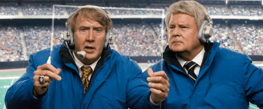 John Madden and Jimmy Johnson holding a clear telestrator screen in a stadium.