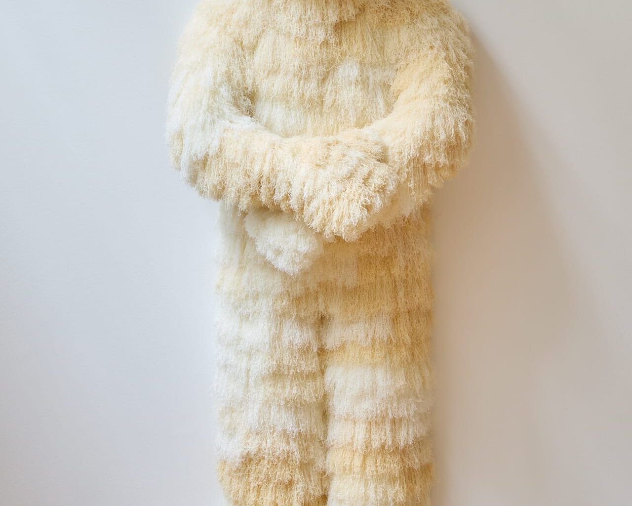 a figurative sculpture by Woo Jin Joo covered in white and beige fur