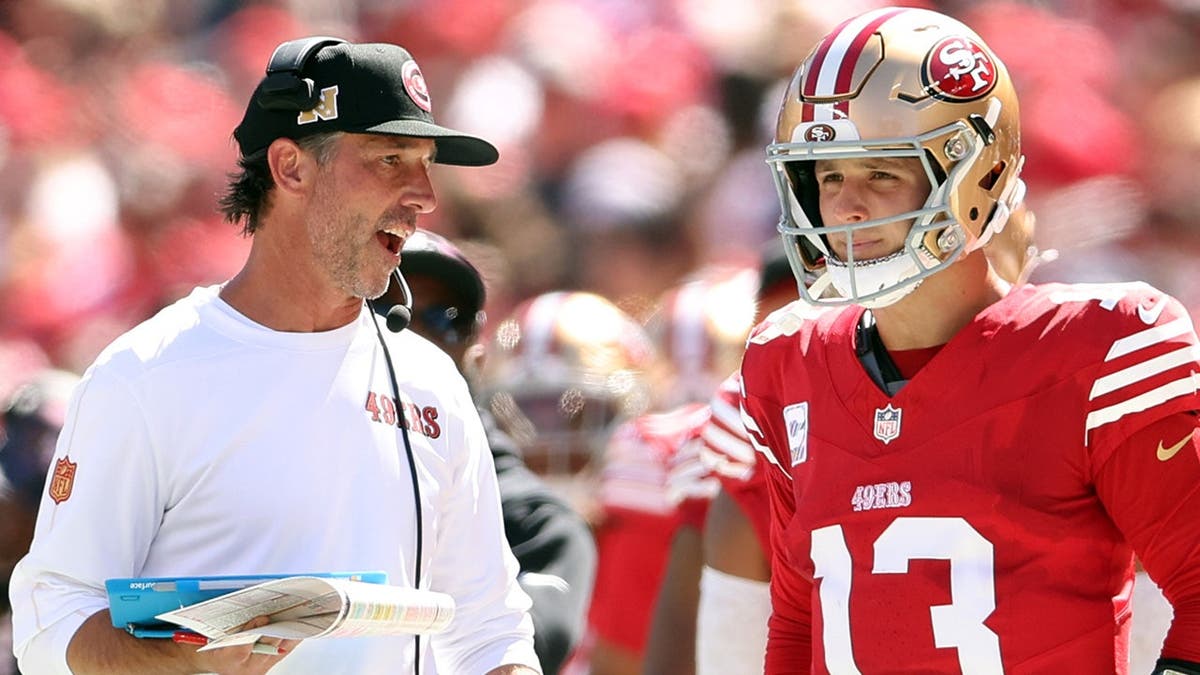 Kyle Shanahan talks with Brock Purdy during an NFL game.