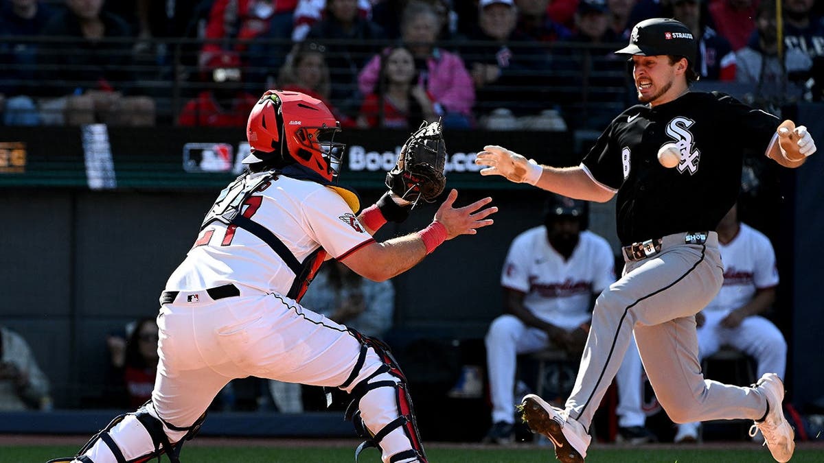 Kyle Teel runs home as Austin Hedges reaches for the throw at home plate.