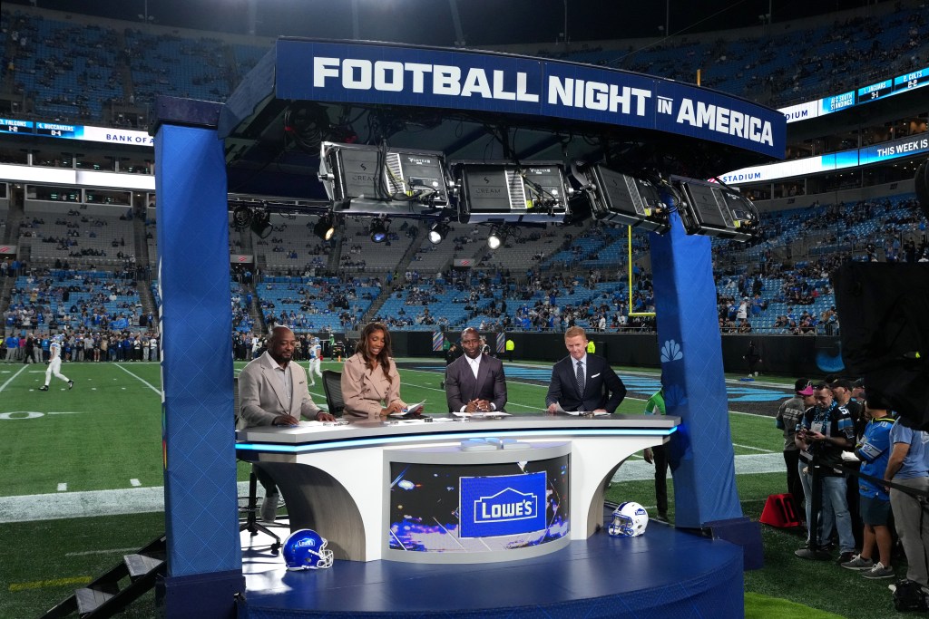 NBC Sports broadcasters Mike Tomlin, Maria Taylor, Devin McCourty and Jason Garrett sit at the Football Night in America desk on the field.