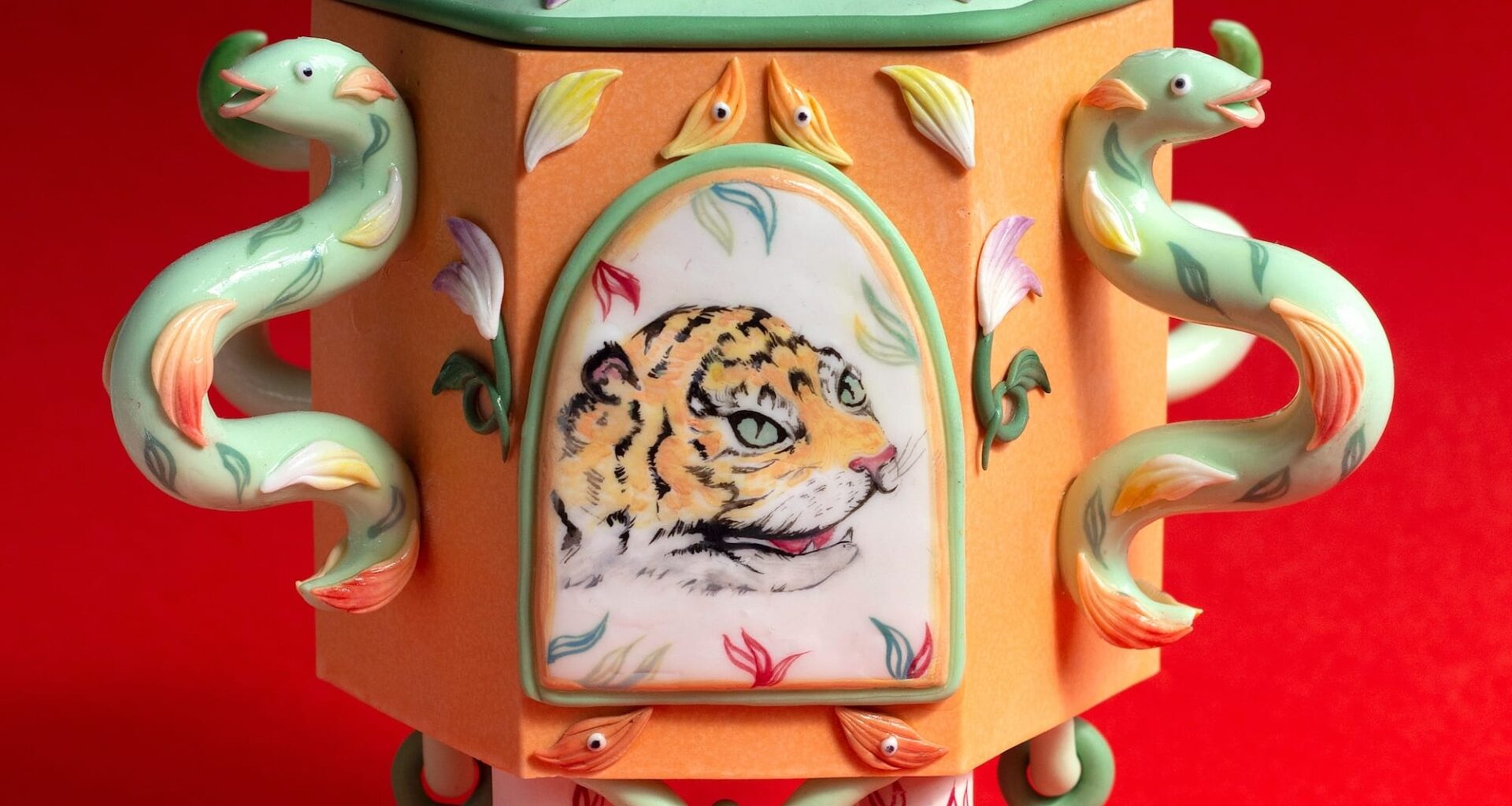 a stylized snuff bottle sculpture made from polymer clay featuring a painting of a small tiger