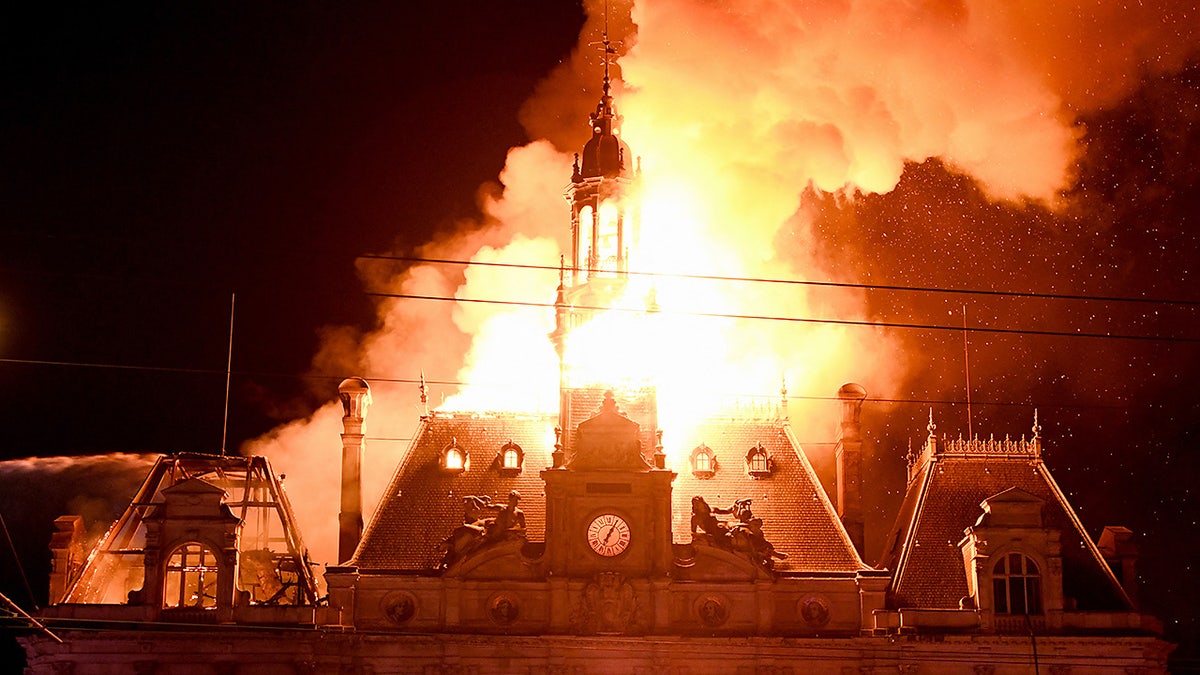 This photograph shows a fire burning and destroying the city hall after a group of individuals forced entry into the building during ongoing protest action against the 