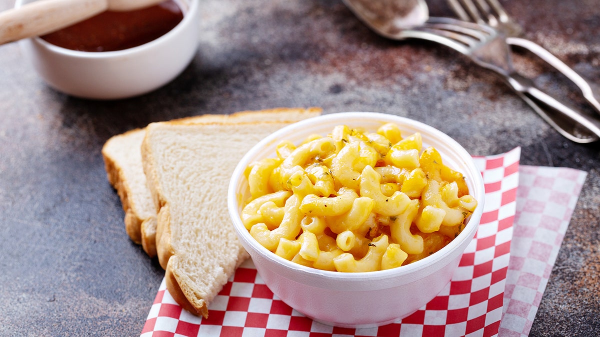Macaroni and cheese in a bowl next to two bread slices