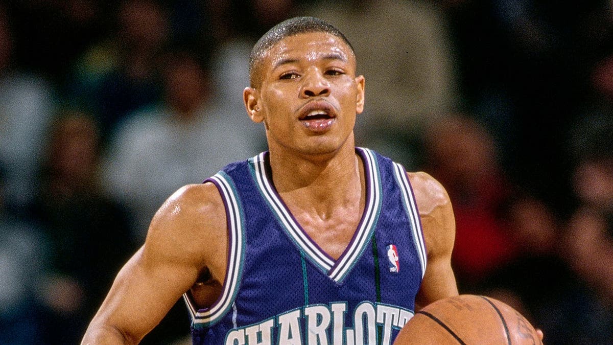 Muggsy Bogues dribbles the basketball down court during an NBA game.