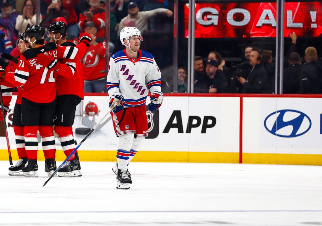New York Rangers center J.T. Miller skates to the bench as New Jersey Devils players celebrate a goal.