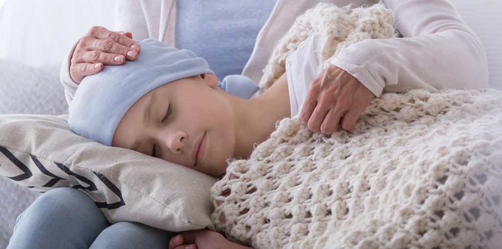 A caregiver supports a sleeping sick child with cancer in the hospice.