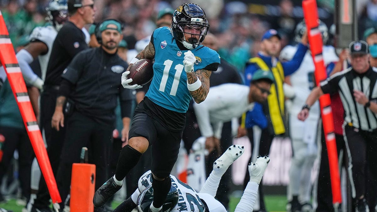 Parker Washington races through to score a touchdown during an NFL game in London.