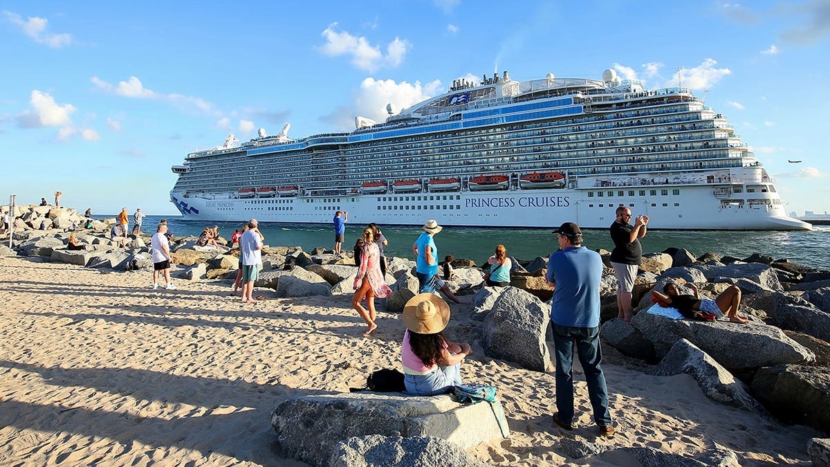 Tourists and sightseers photograph departing cruise ships at Port Everglades jetty.