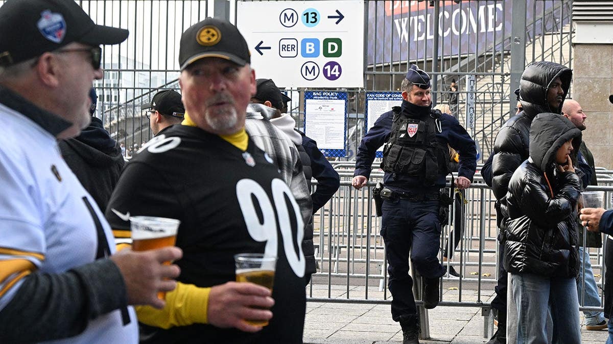 Police officer stands outside Stade de France stadium before NFL game.