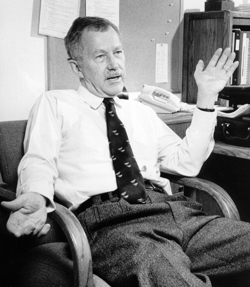 black and white photo of man with mustache sitting in chair gesturing