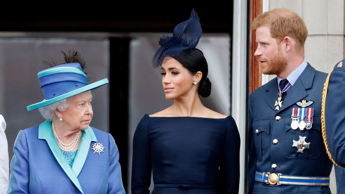 Queen Elizabeth II, Meghan, Duchess of Sussex and Prince Harry watch a Royal Air Force flypast from Buckingham Palace balcony.