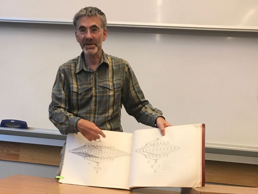 UC Berkeley professor and Fields medalist Richard Borcherds holding open a book with mathematical diagrams.