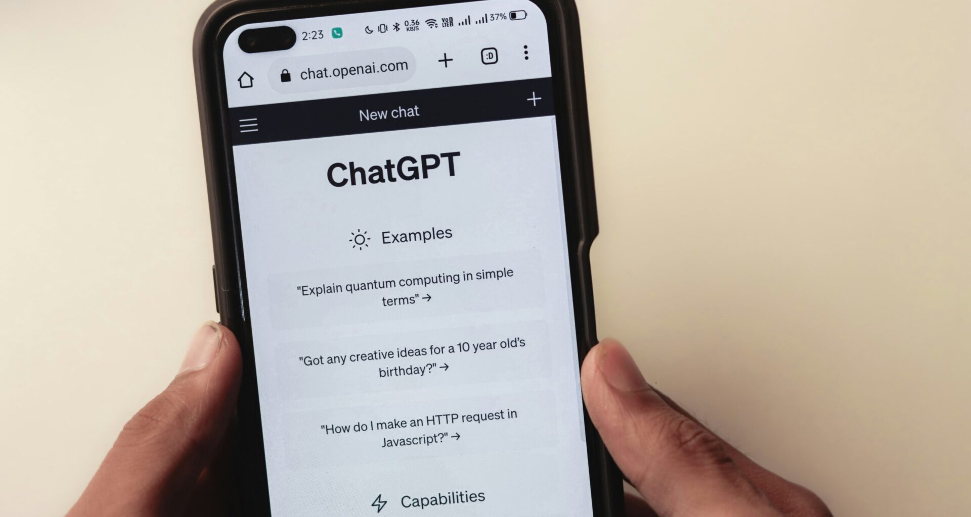 A person holds a cell phone open to a ChatGPT webpage, which is prompting the user to ask a series of questions.