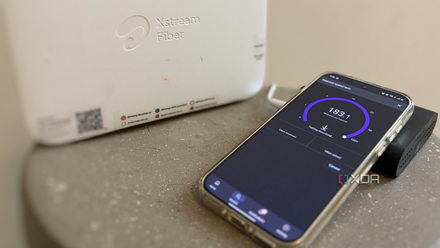 A smartphone running a Wi-Fi speed test next to a white router