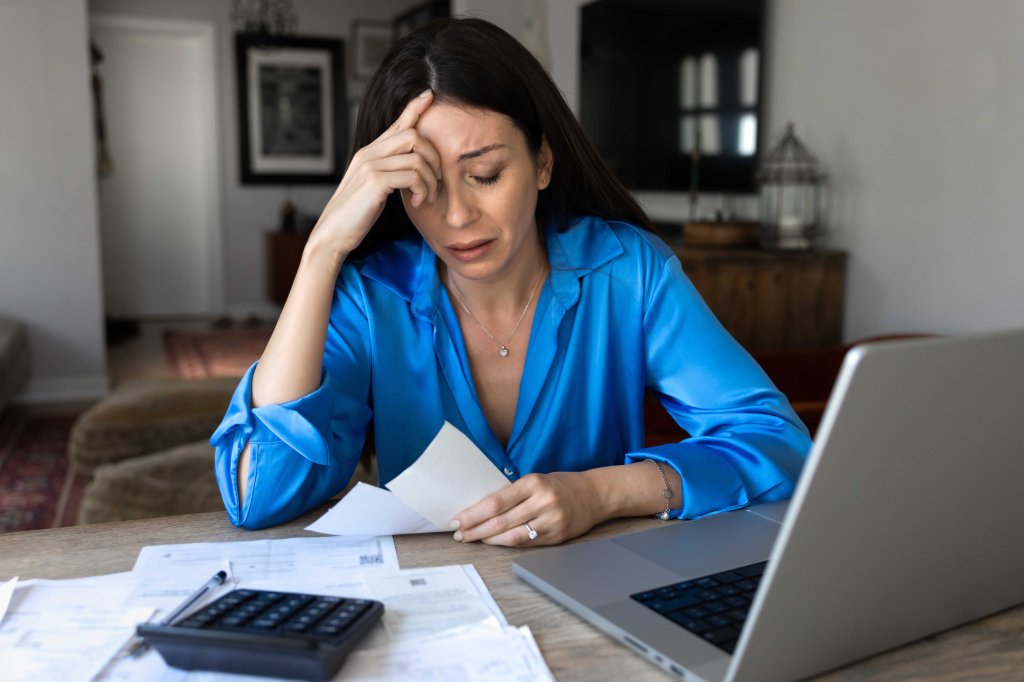 A stressed woman looks at household bills.
