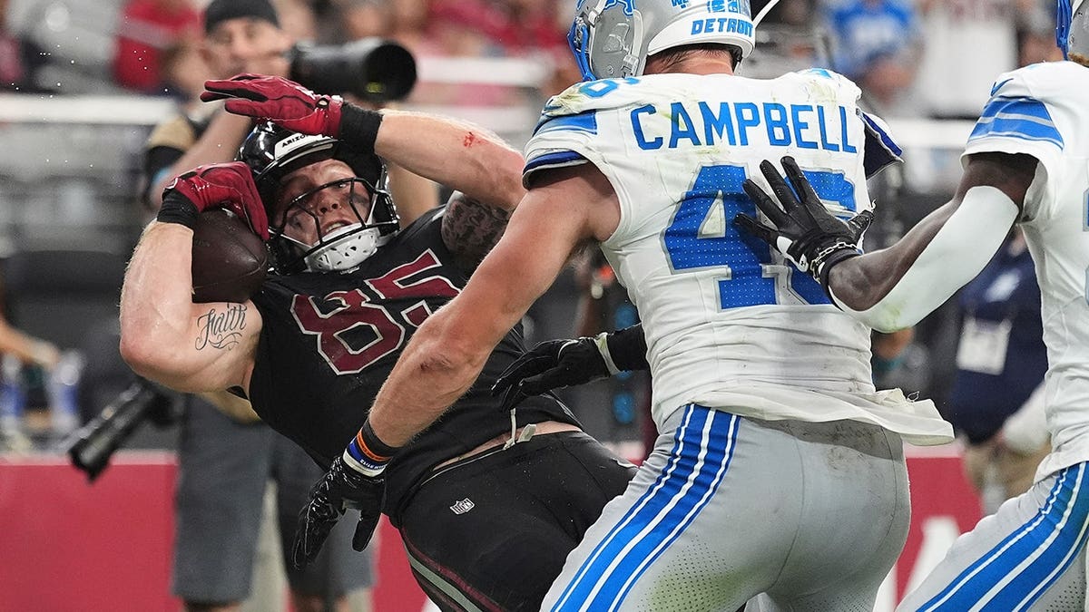 Trey McBride catches a touchdown pass while Jack Campbell defends during an NFL game.